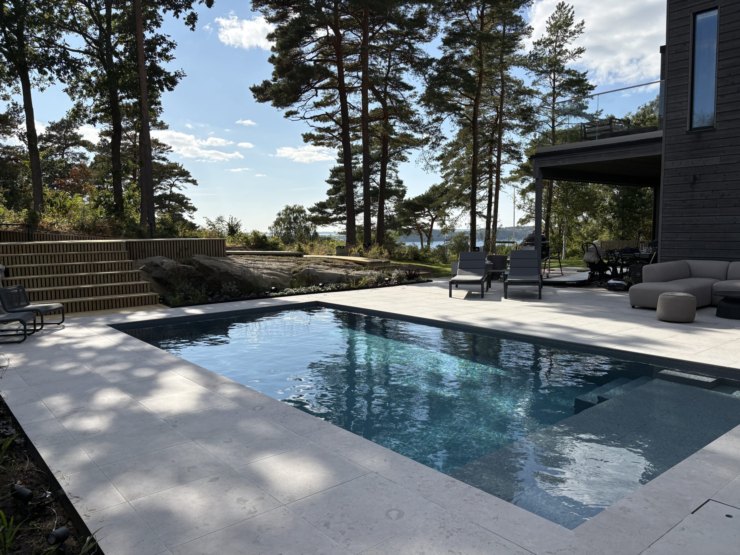 Pool vid svart hus med utsikt och berg - Natalia Lindberg trädgårdsdesign