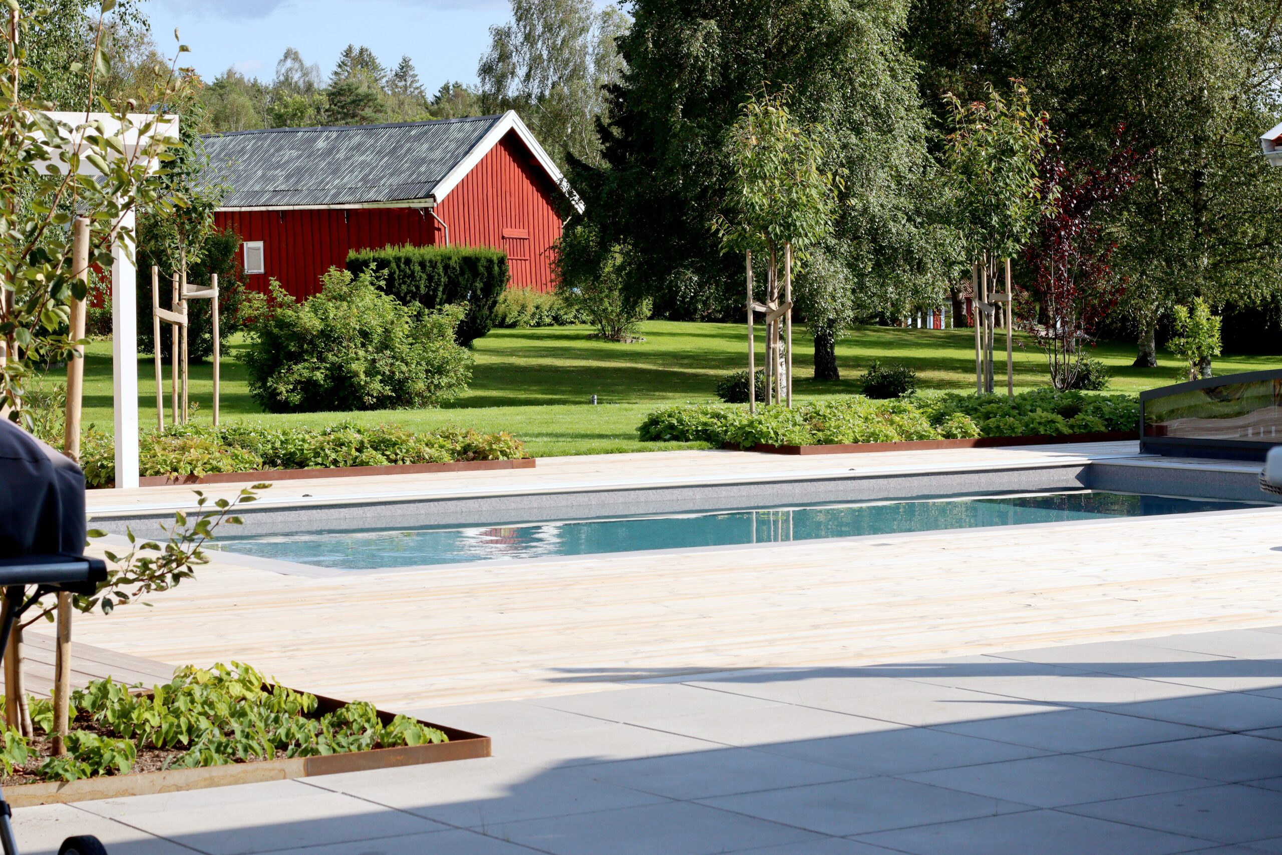 Poolträdgård i lantlig miljö med pool och trädäck - natalia lindberg trädgårdsdesign